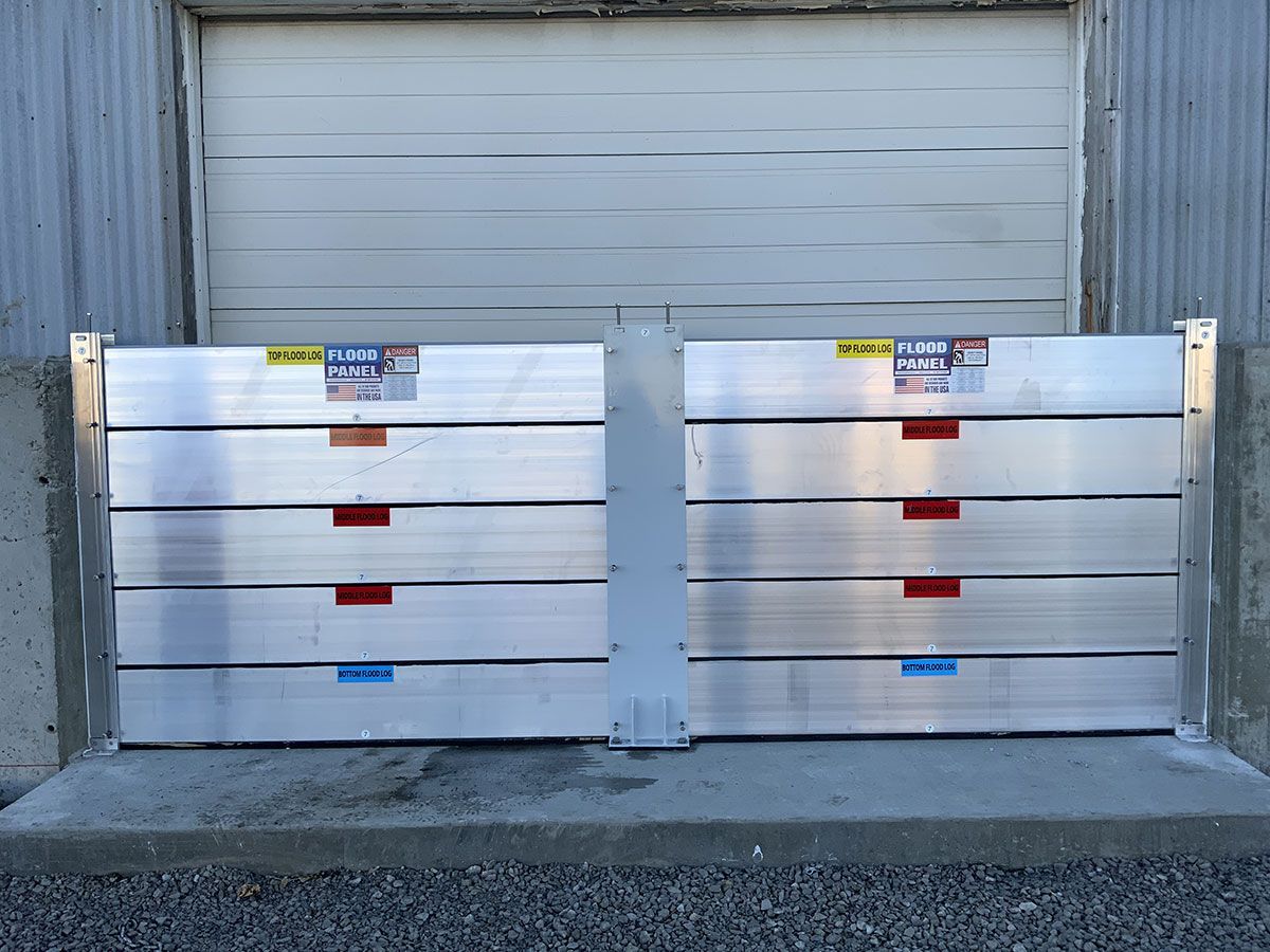 A pair of aluminum flood barriers are sitting in front of a garage door.