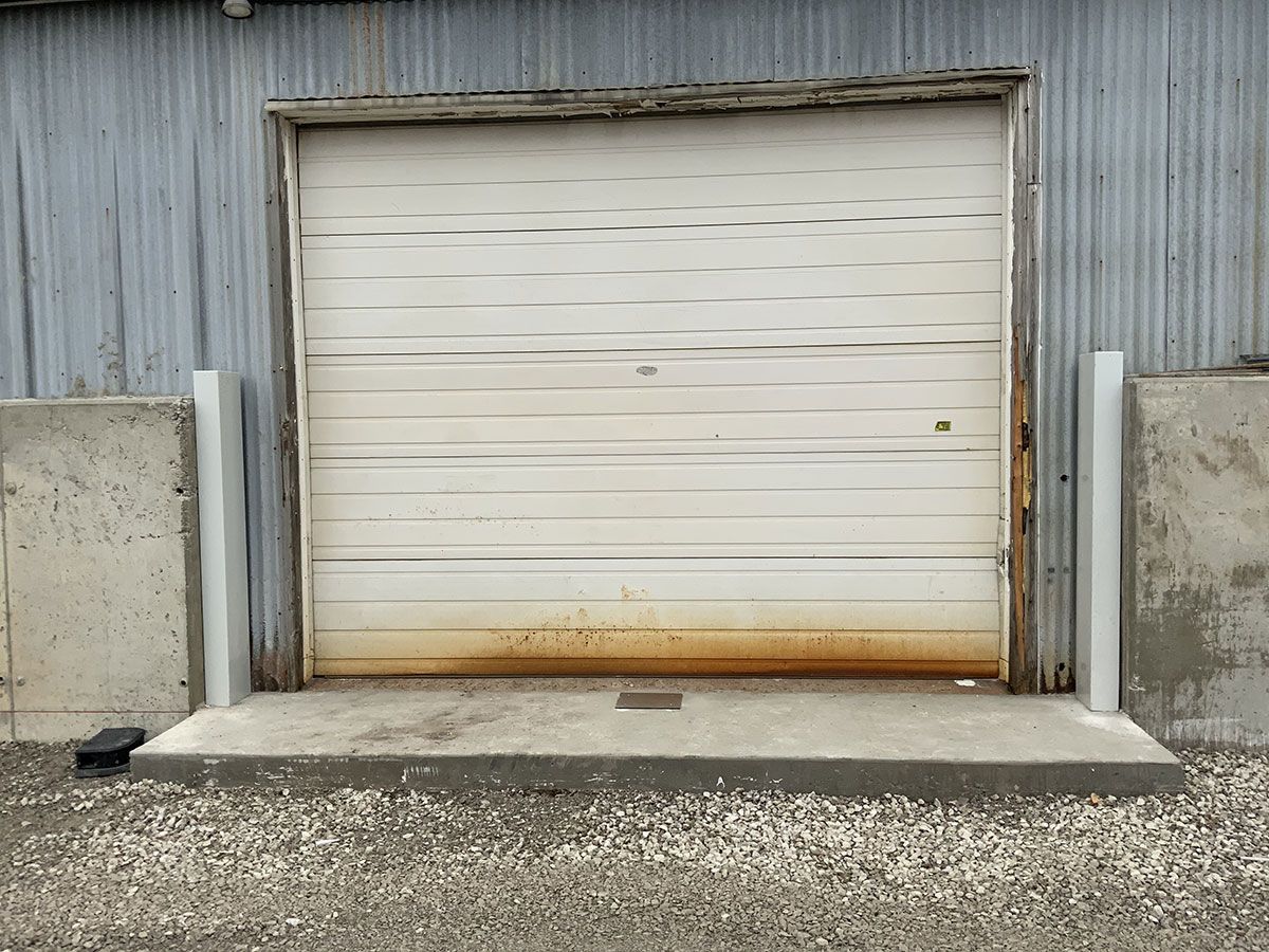A white garage door is sitting in front of a building.