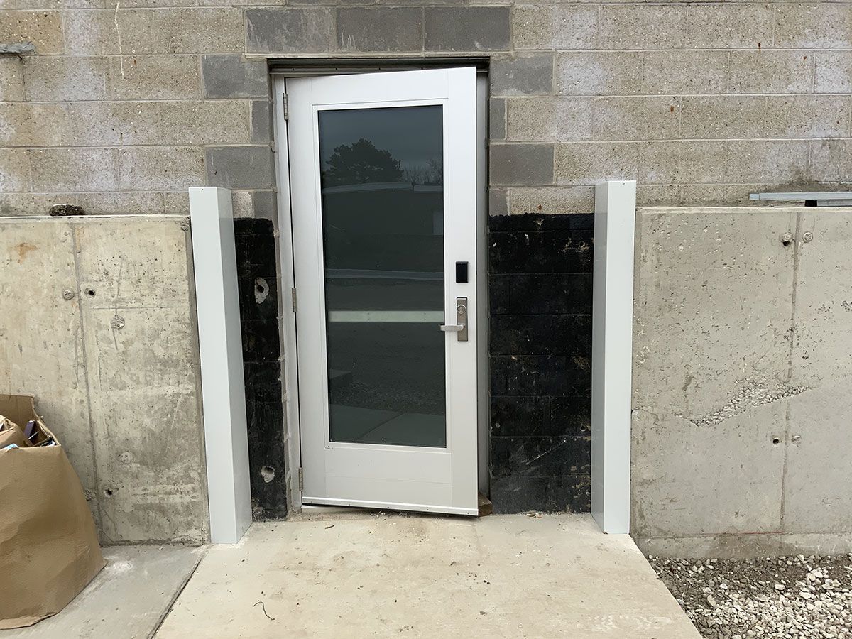 A white door with a glass window is sitting in front of a brick wall.