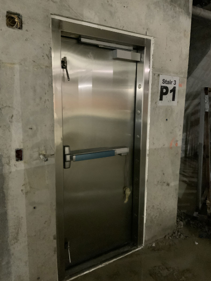 A stainless steel door with a sign on the wall that says p1