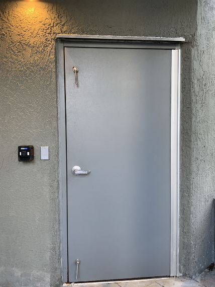 A gray door is sitting on a wall next to a mailbox.