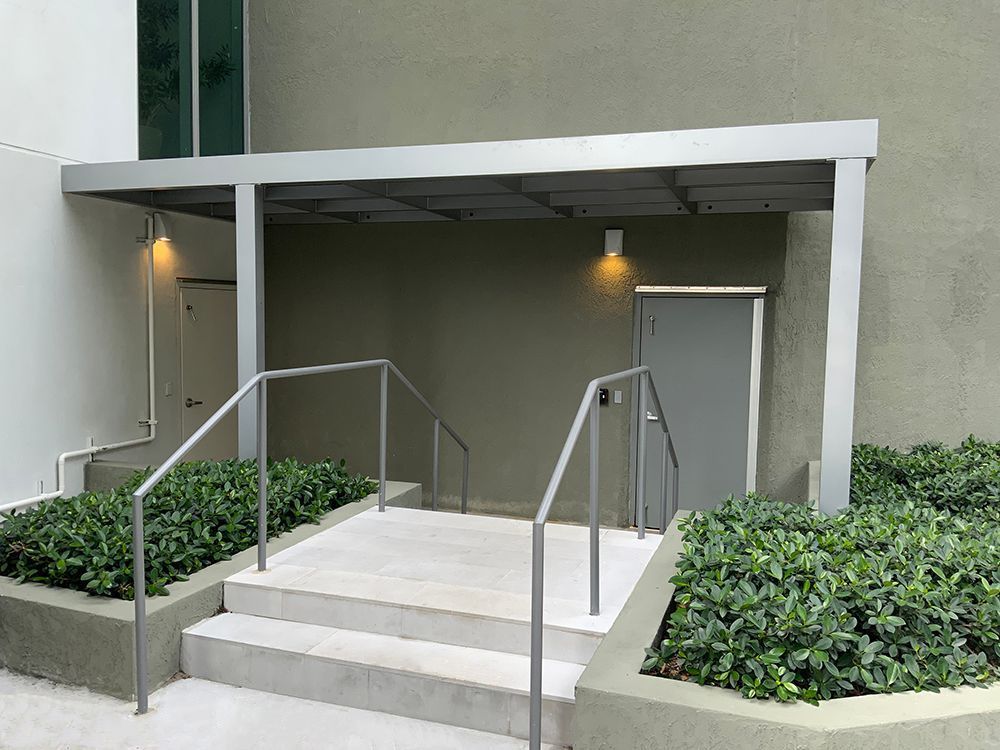 A building with stairs leading up to a door and a canopy over it.