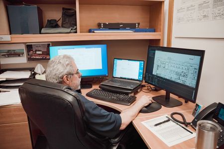 A man is sitting at a desk in front of two computer monitors.