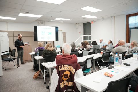 A man is giving a presentation to a group of people in a classroom.