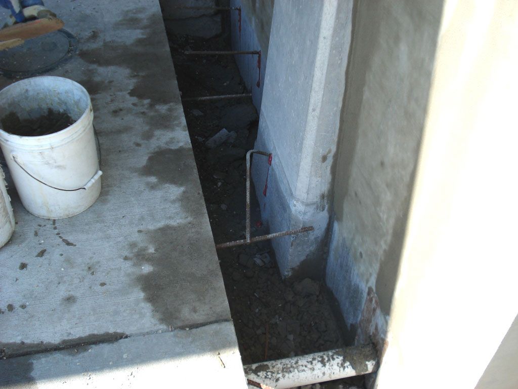 A bucket of cement is sitting on the ground next to a wall.