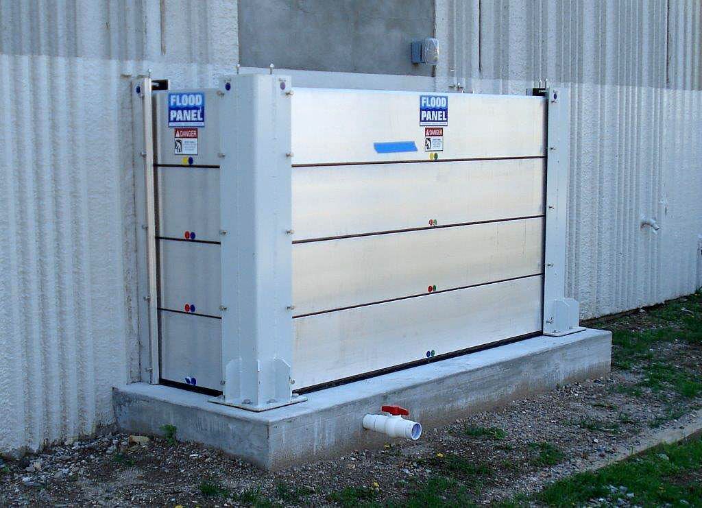 A stainless steel flood barrier is sitting in front of a building