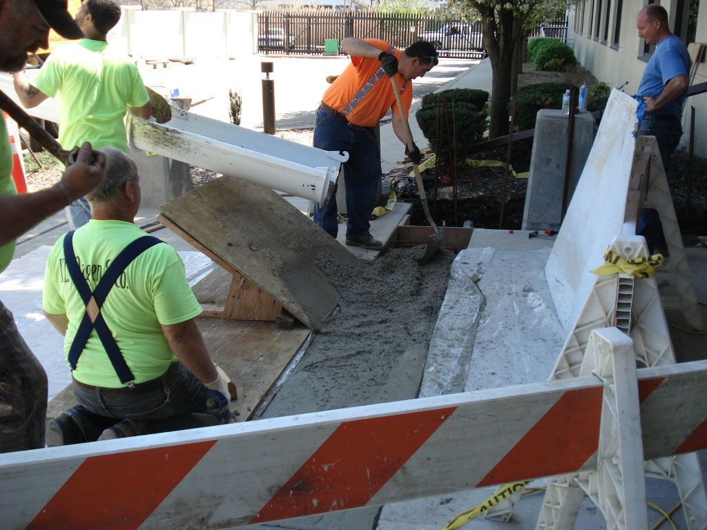 A group of construction workers are working on a sidewalk