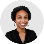 A woman wearing a black shirt and hoop earrings is smiling for the camera.