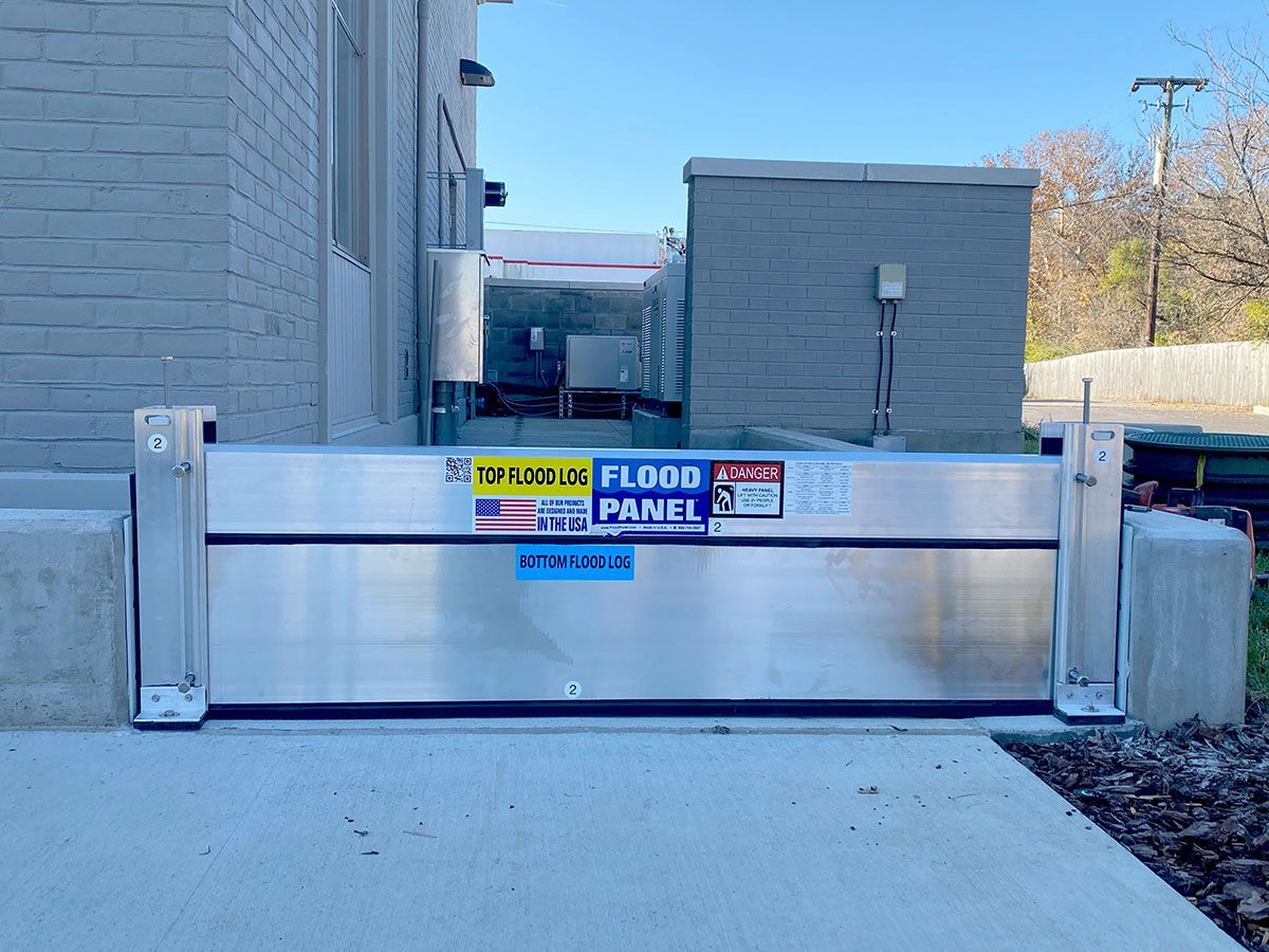 A flood panel is sitting on the sidewalk in front of a building.