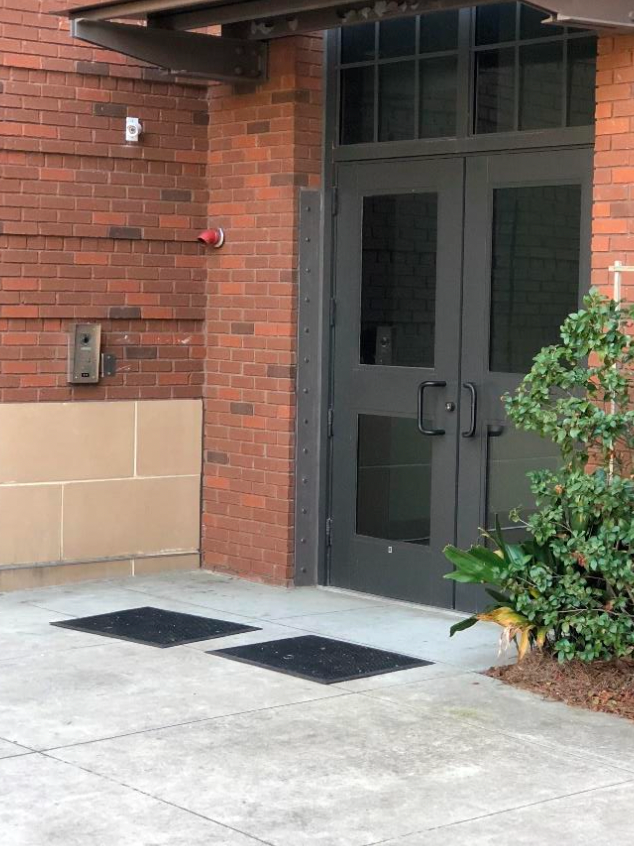 A brick building with a black door and a fire alarm