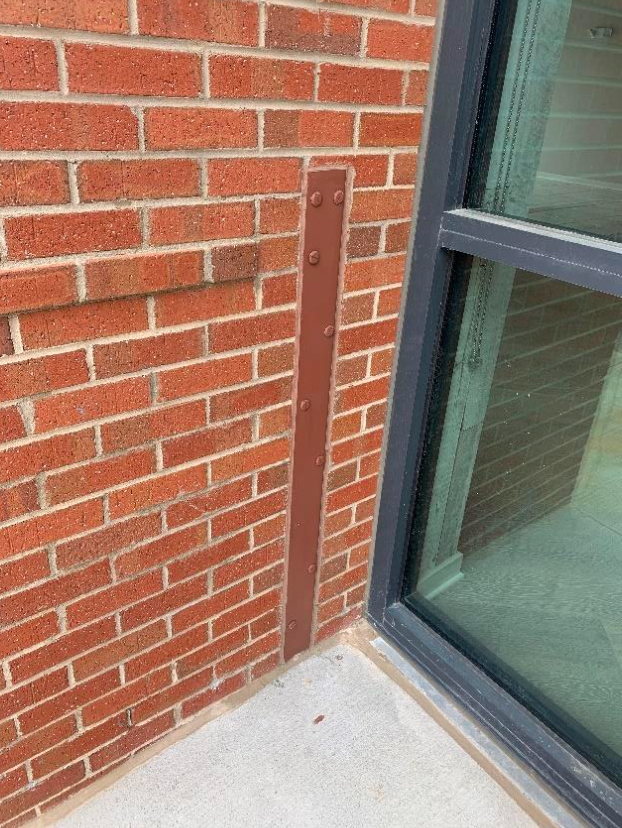 A brick wall with a metal bar attached to it next to a window.