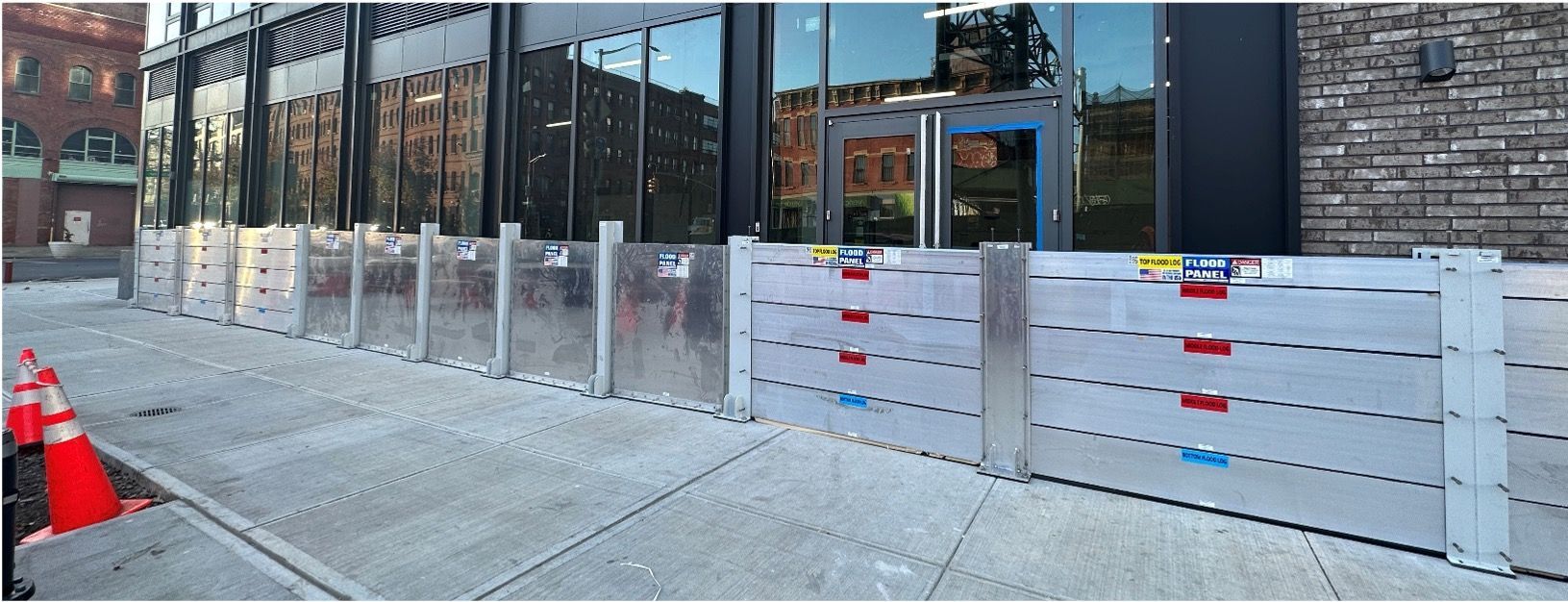 A flood barrier is sitting on the sidewalk in front of a building.