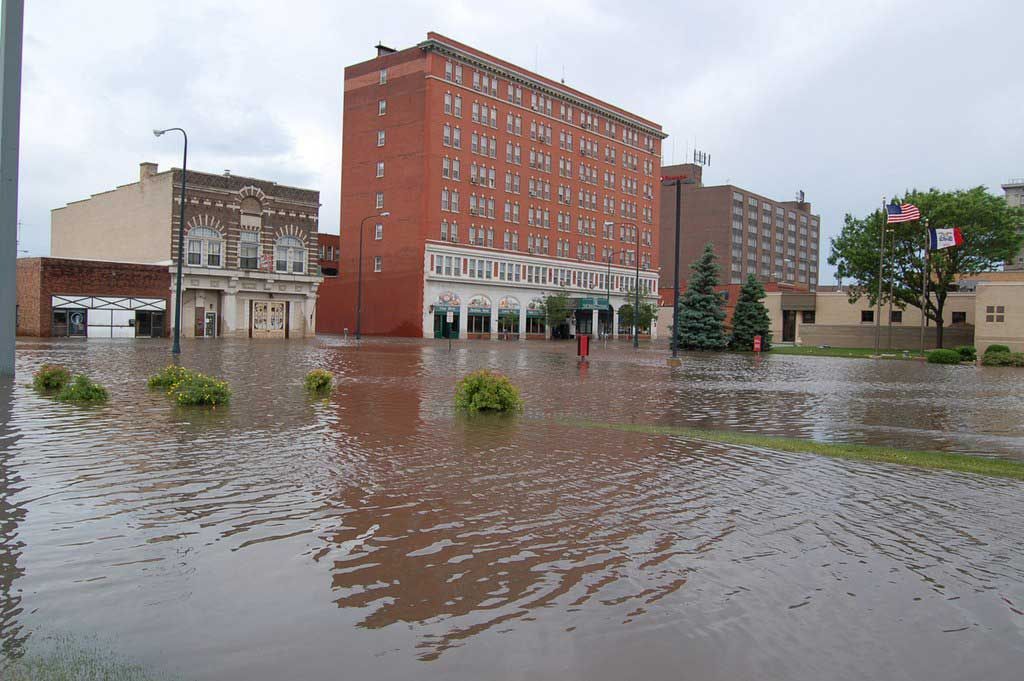 A flooded street with a large building in the background