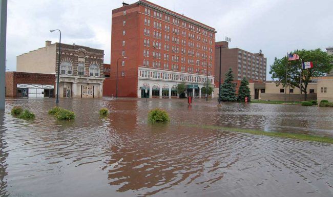 A flooded city street with a large building in the background.