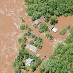 An aerial view of a flooded area with houses and trees.