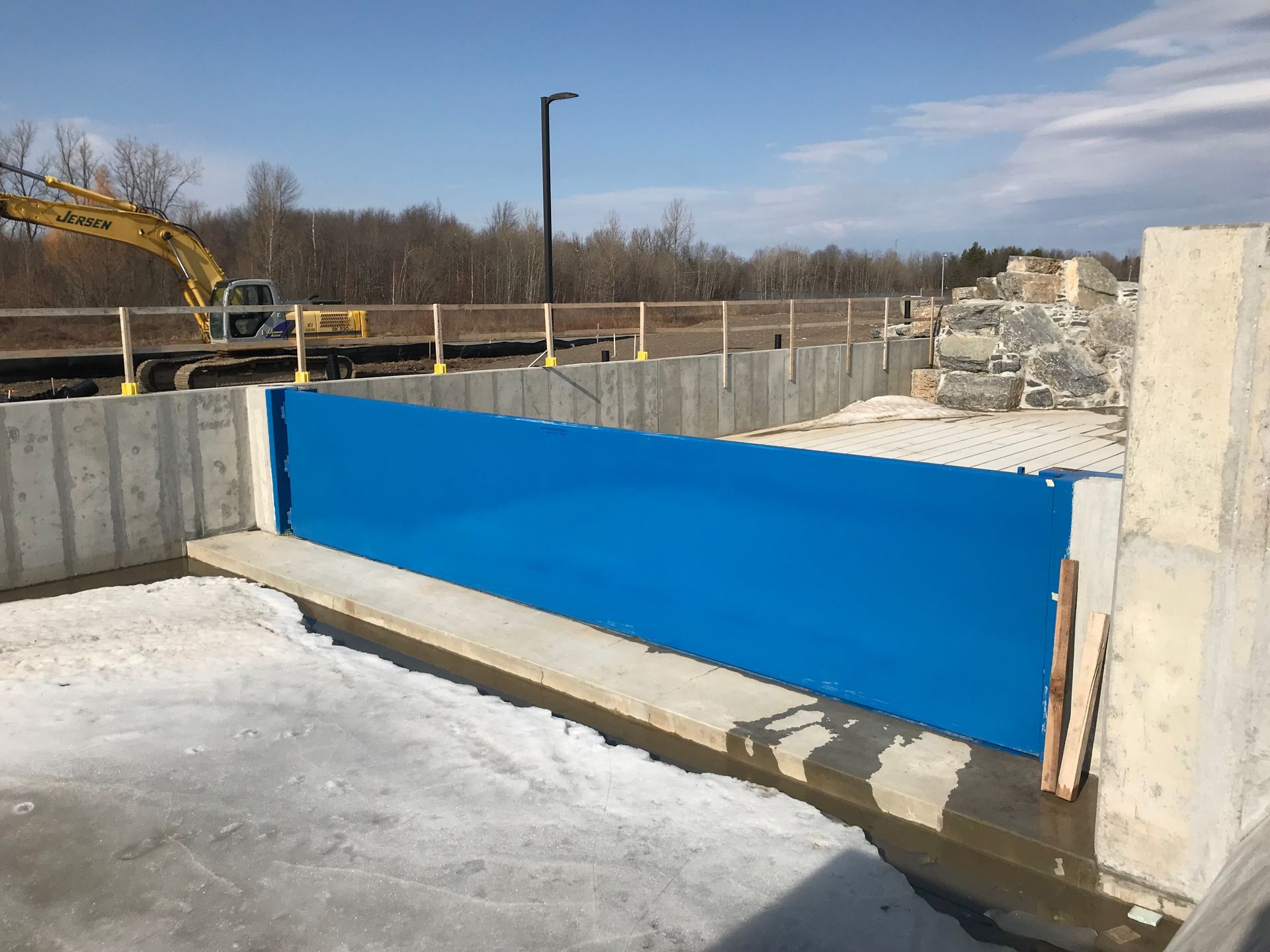 A construction site with a blue barrier and a yellow excavator in the background