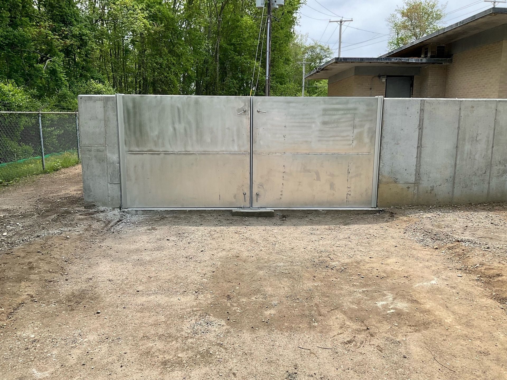 A metal gate is sitting in the dirt in front of a building.