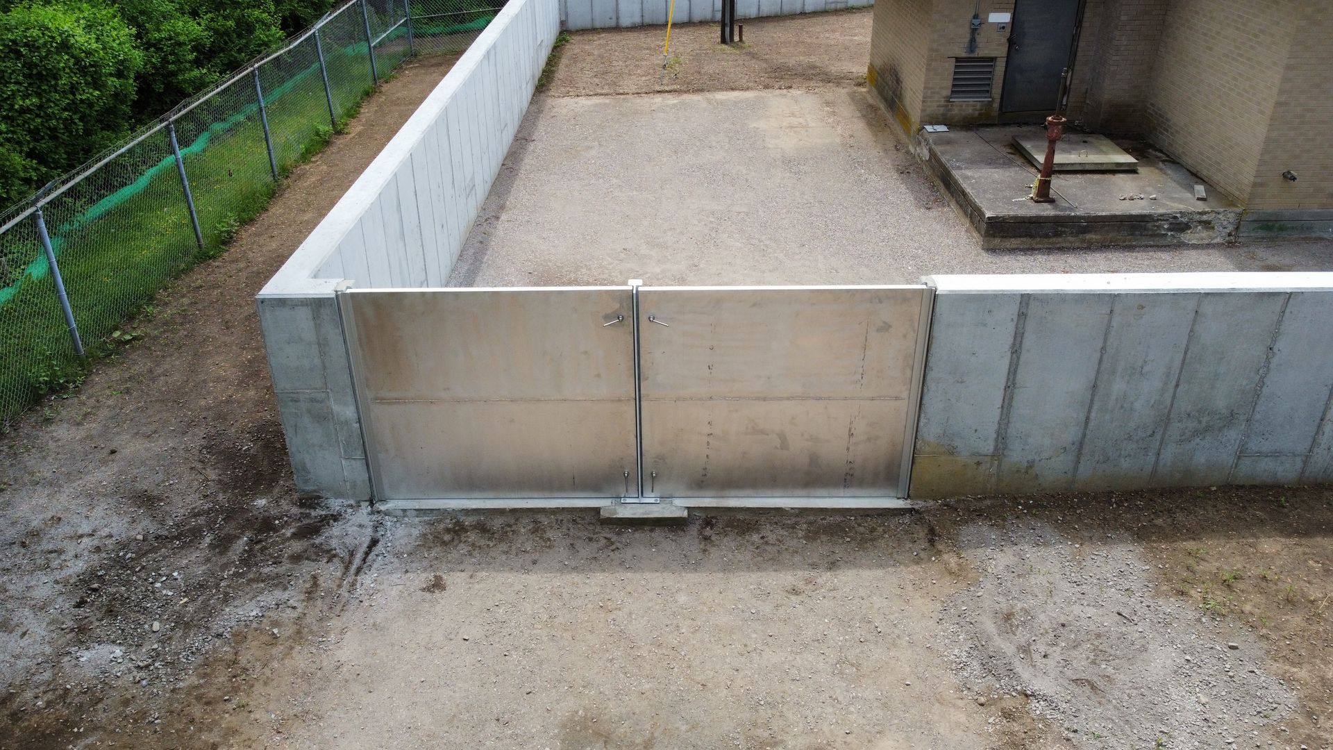 A concrete wall with a metal gate in front of a building.