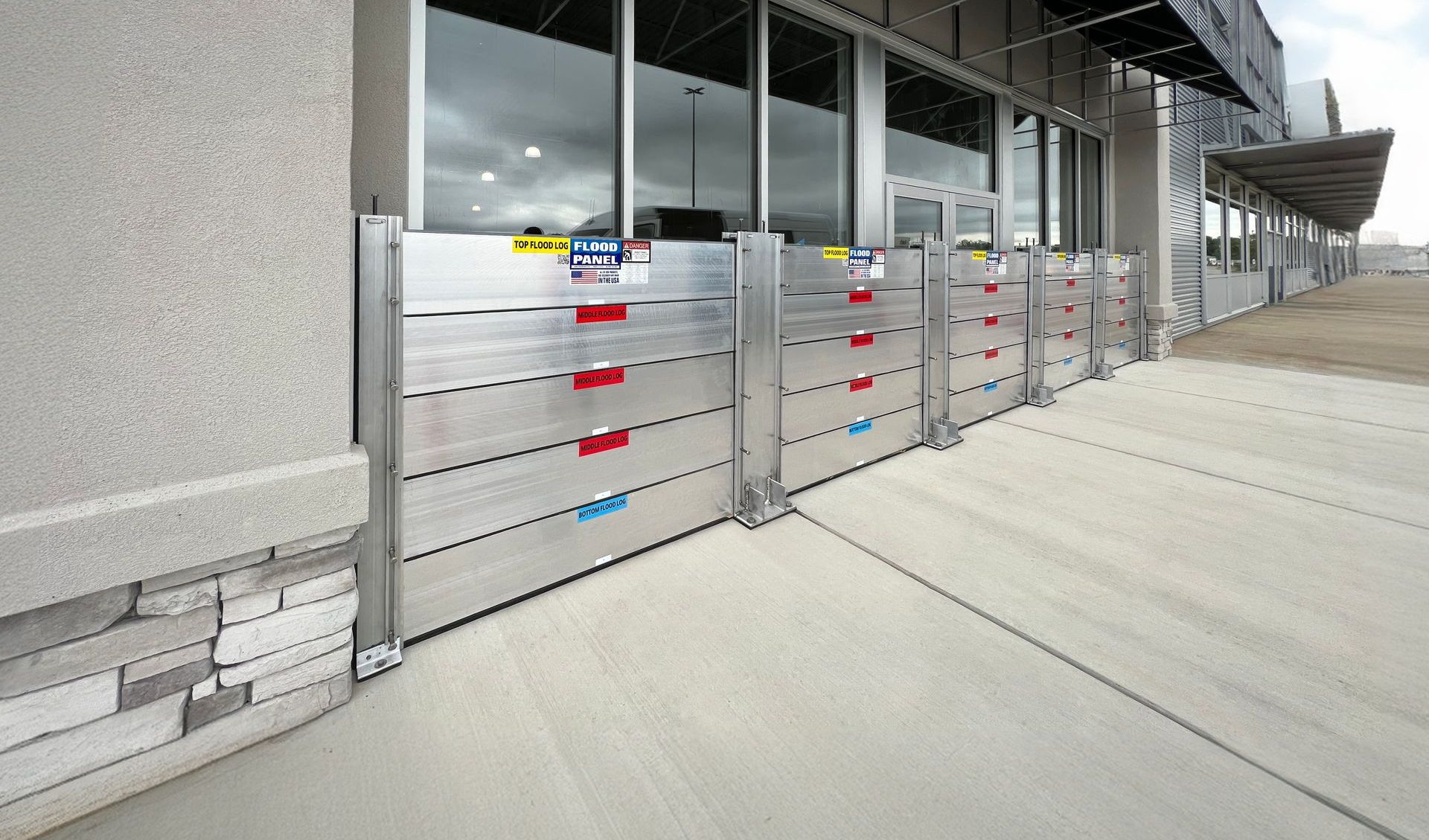 A row of aluminum flood barriers on the sidewalk in front of a building.