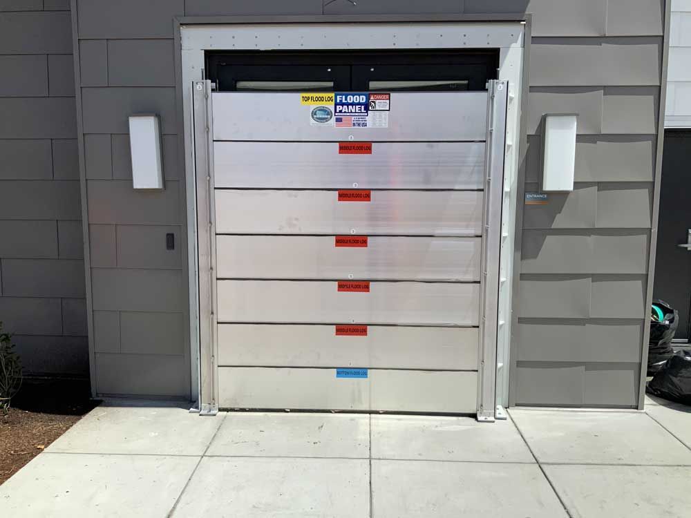 A flood barrier is sitting on the sidewalk in front of a building.