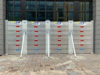 A row of aluminum flood barriers are lined up in front of a building.
