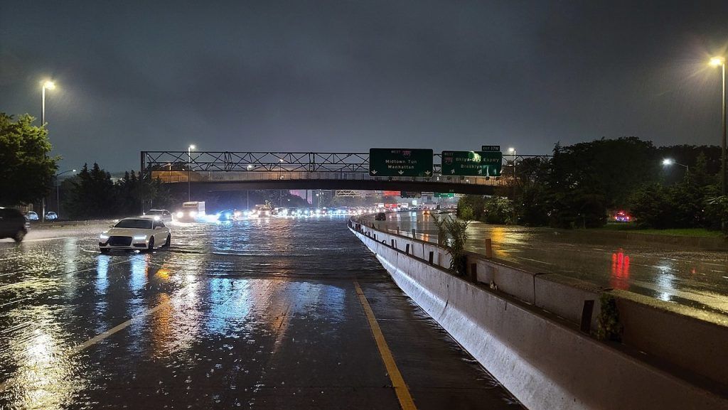 A flooded highway at night with a bridge in the background.