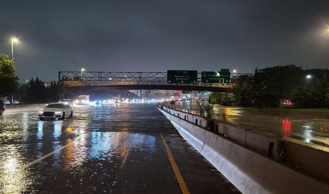 A flooded highway at night with a bridge in the background.