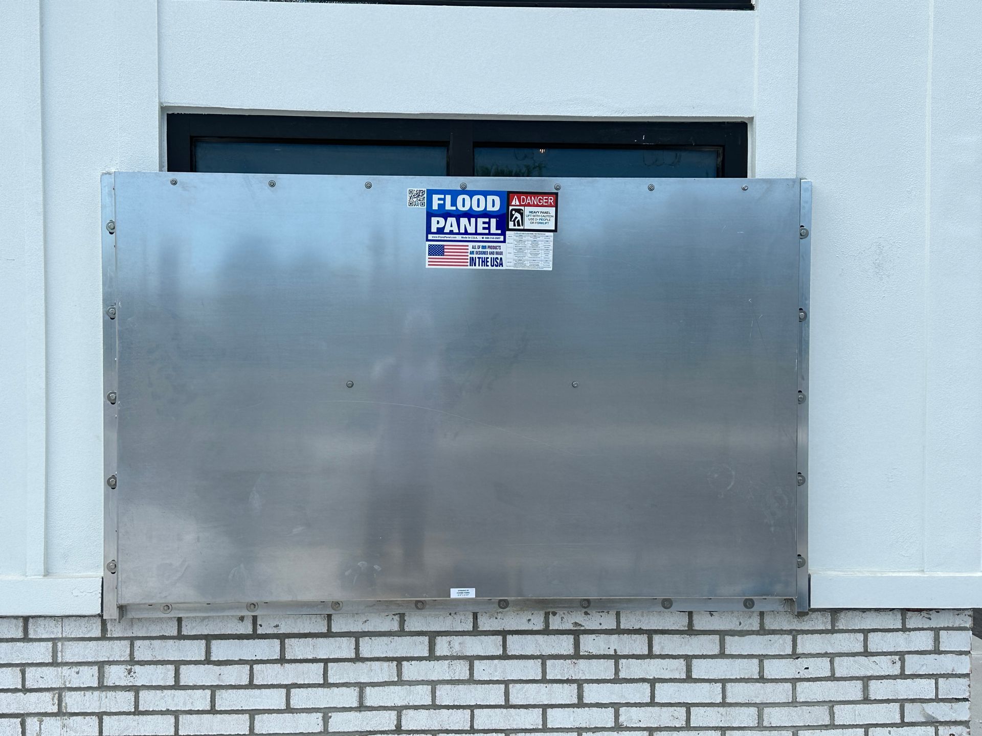 A stainless steel flood panel is attached to the side of a building