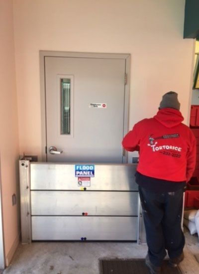 A man in a red hoodie is standing in front of a door