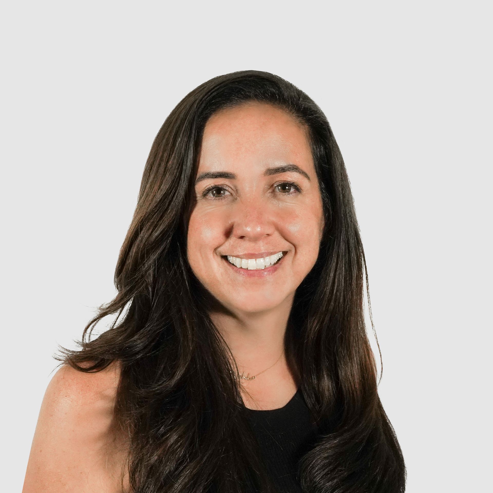 A woman with long hair is smiling and wearing a black tank top