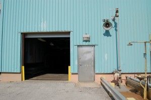 A blue building with a door and a speaker on the side.