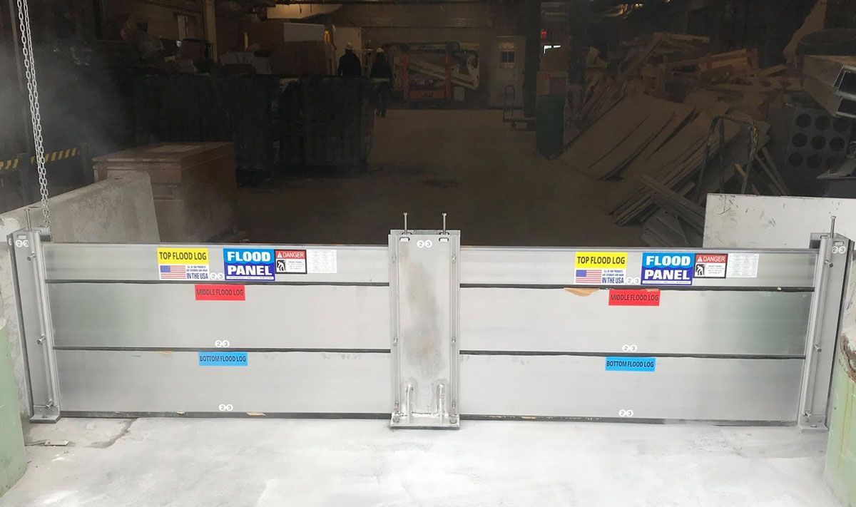 A stainless steel flood barrier is sitting in a warehouse.