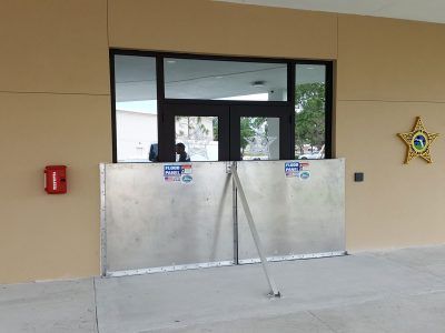 A fire extinguisher is on the side of a building next to a window.