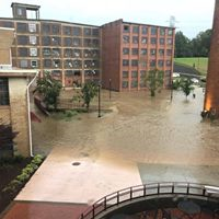 A large brick building is surrounded by a flooded courtyard.