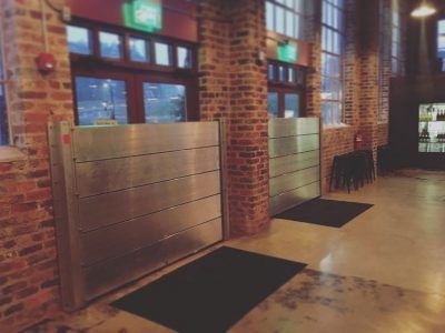 A hallway with a brick wall and a metal barrier.