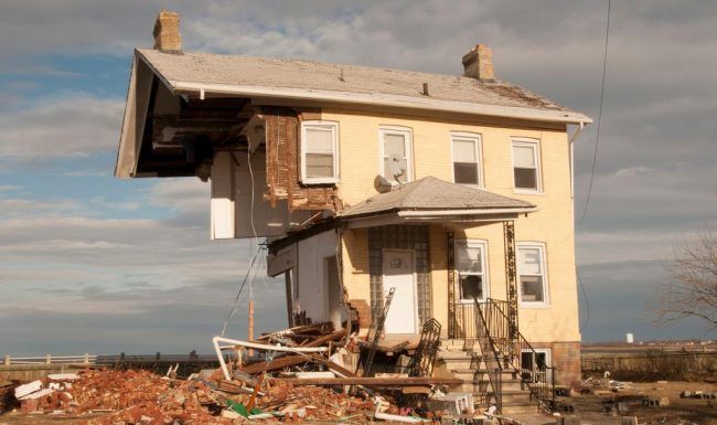 A yellow house is sitting on top of a pile of rubble.