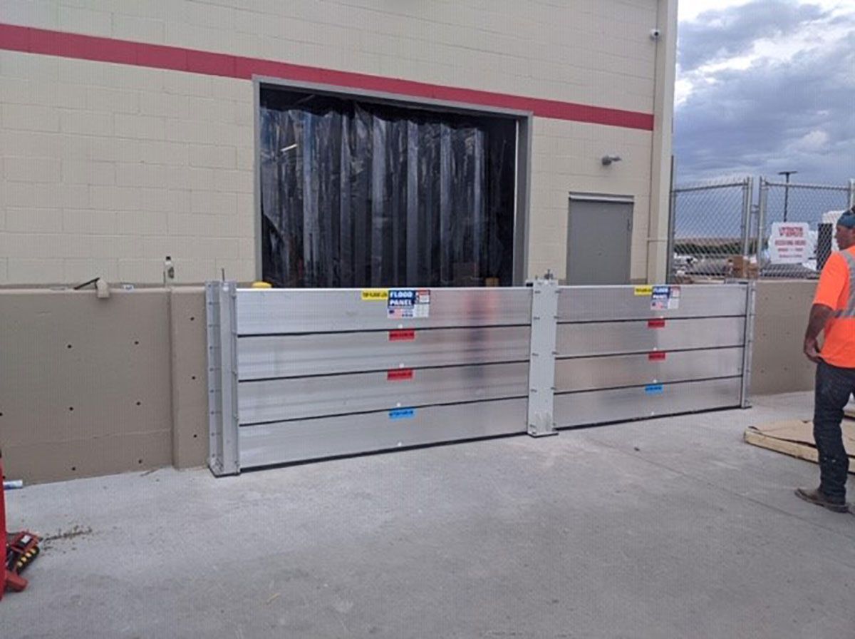 A man in an orange vest is standing in front of a flood barrier