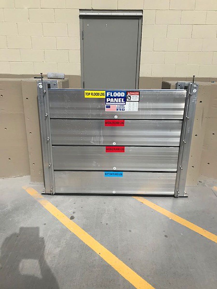 A flood panel is sitting in a parking lot next to a door.