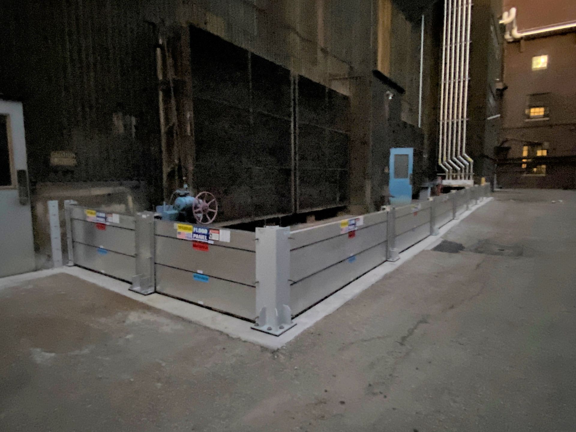 A flood barrier is sitting on the side of a road in front of a building.