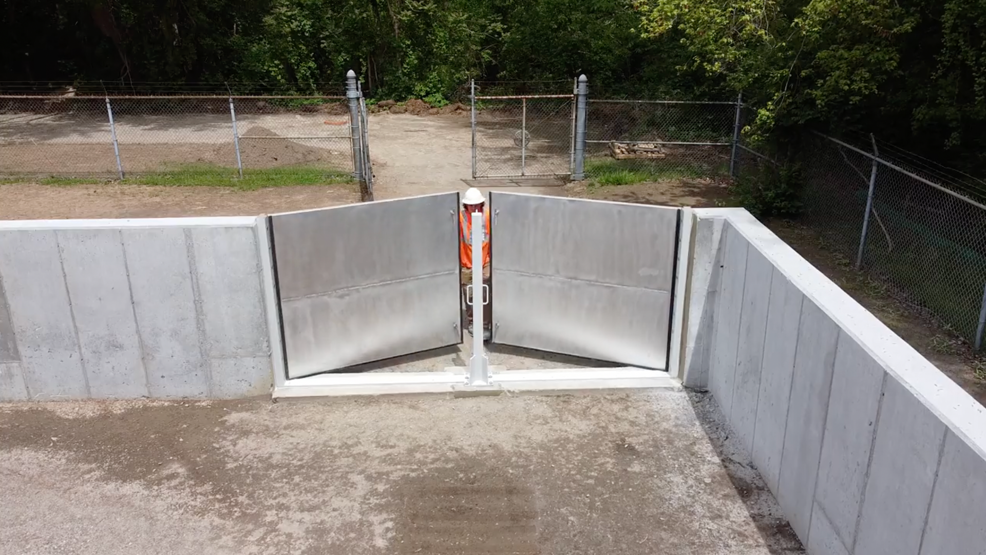 A concrete wall with a metal gate in the middle of it.