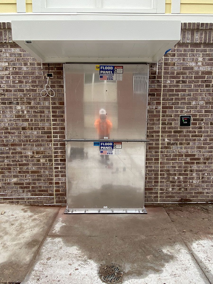 A man is standing in front of a brick building with a stainless steel door.