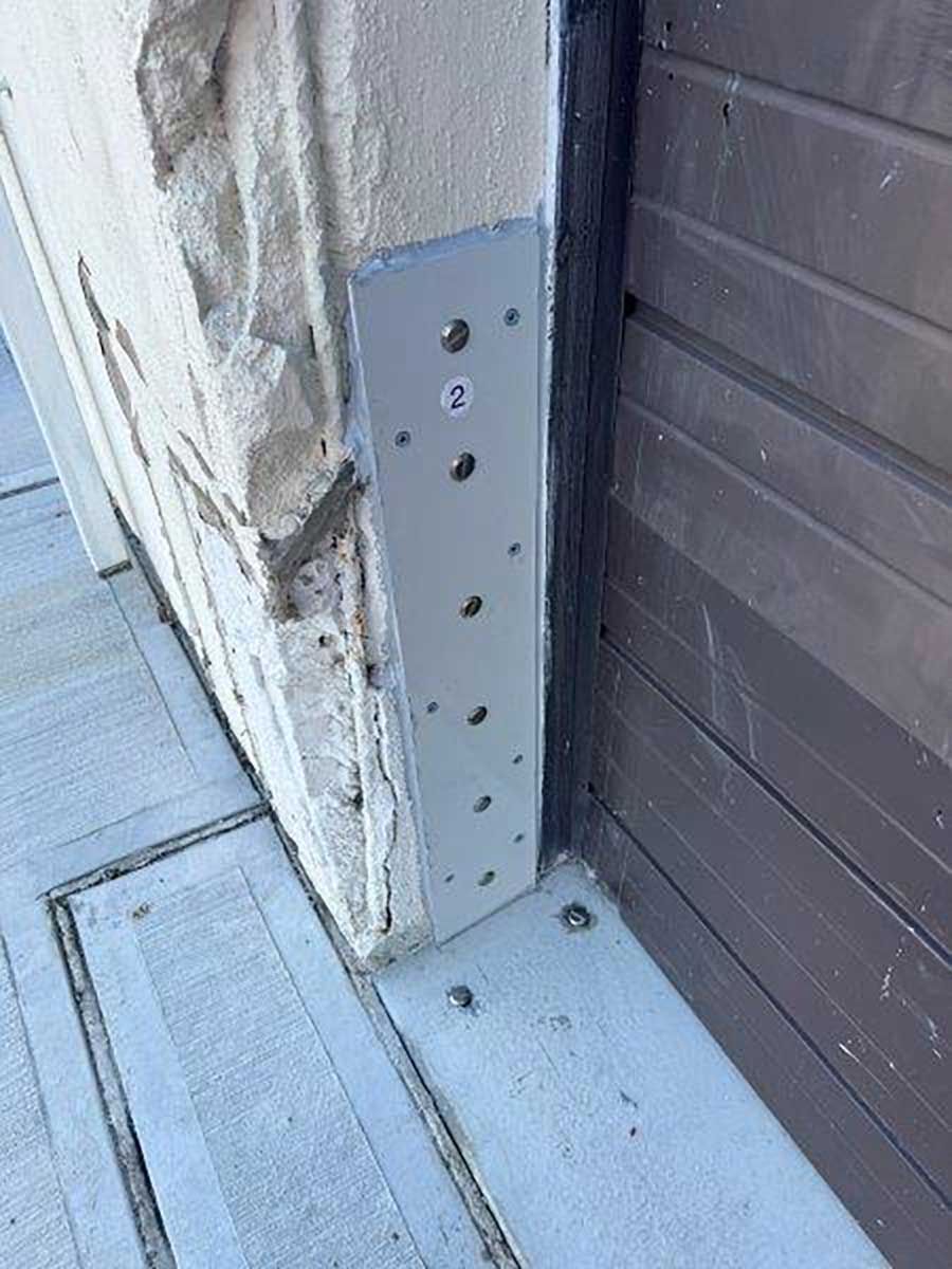 A metal bracket is attached to the side of a building.