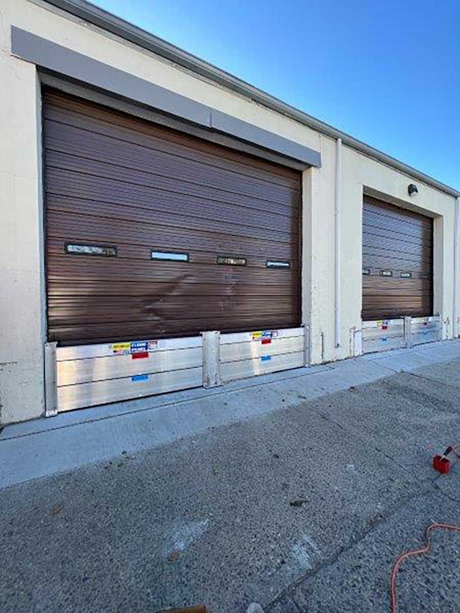 A row of garage doors with flood barriers on the side of a building.