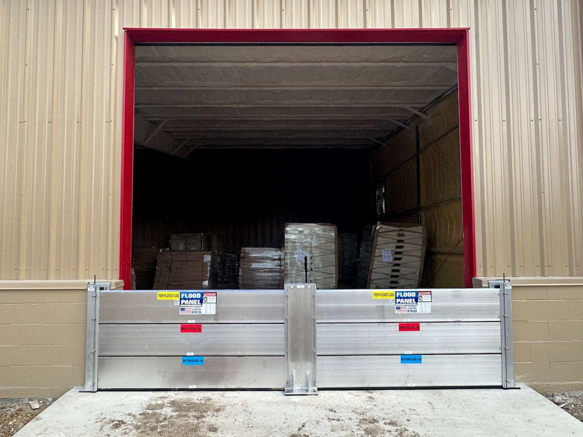A warehouse with a door open and a flood barrier in front of it.