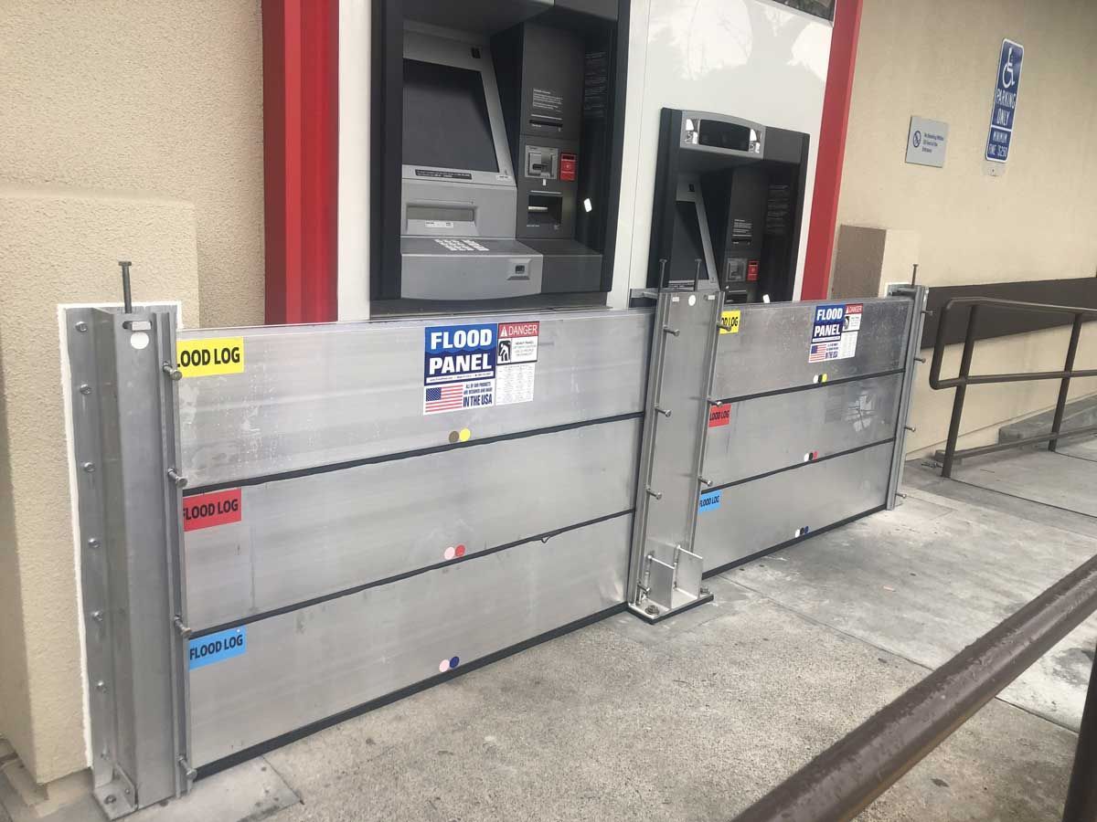 A flood barrier is sitting next to an atm machine.