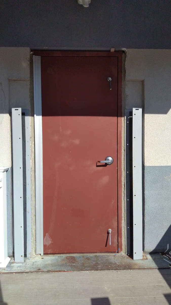 A red door is sitting on the side of a building.