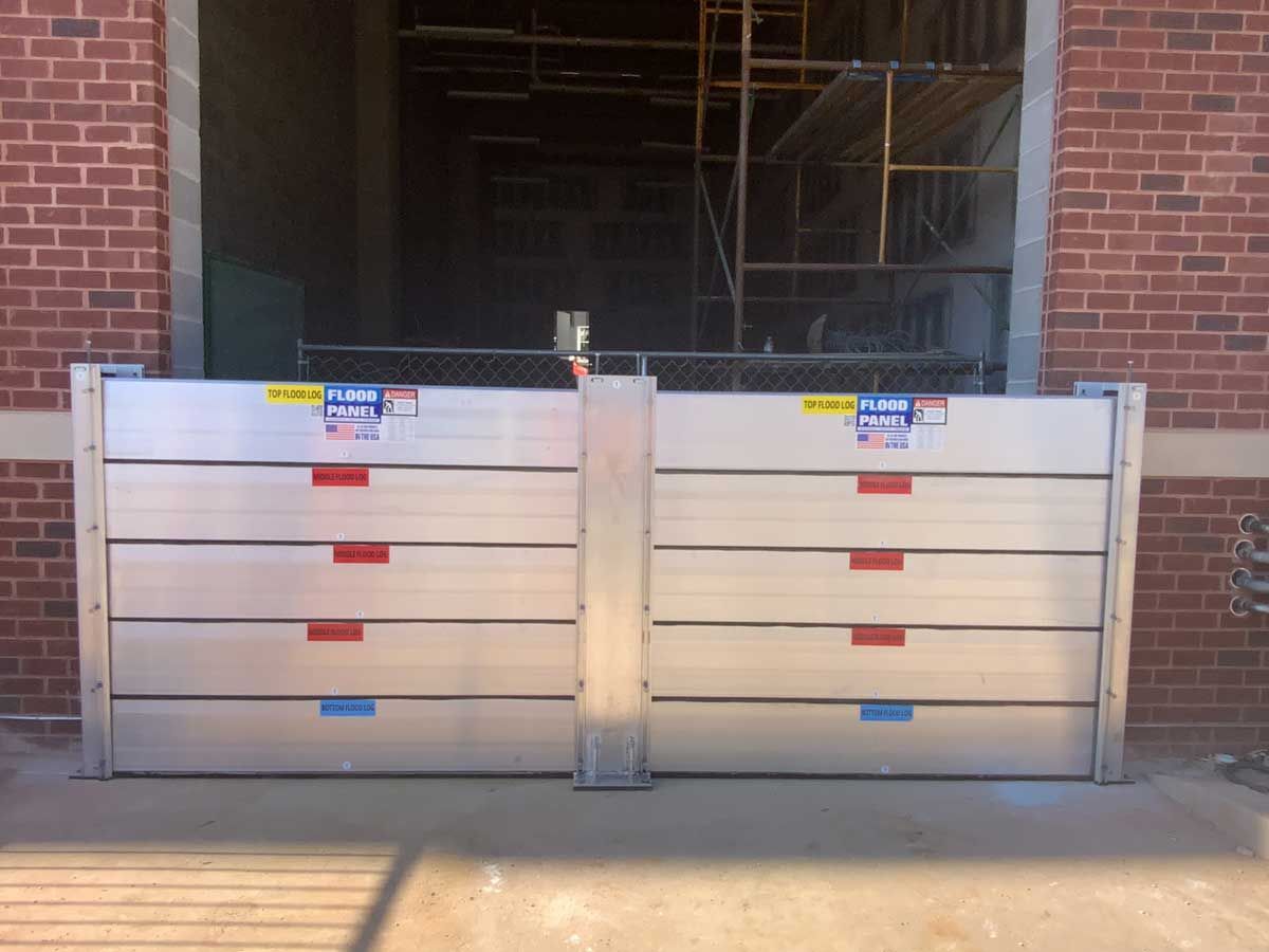 A pair of aluminum flood barriers in front of a brick building