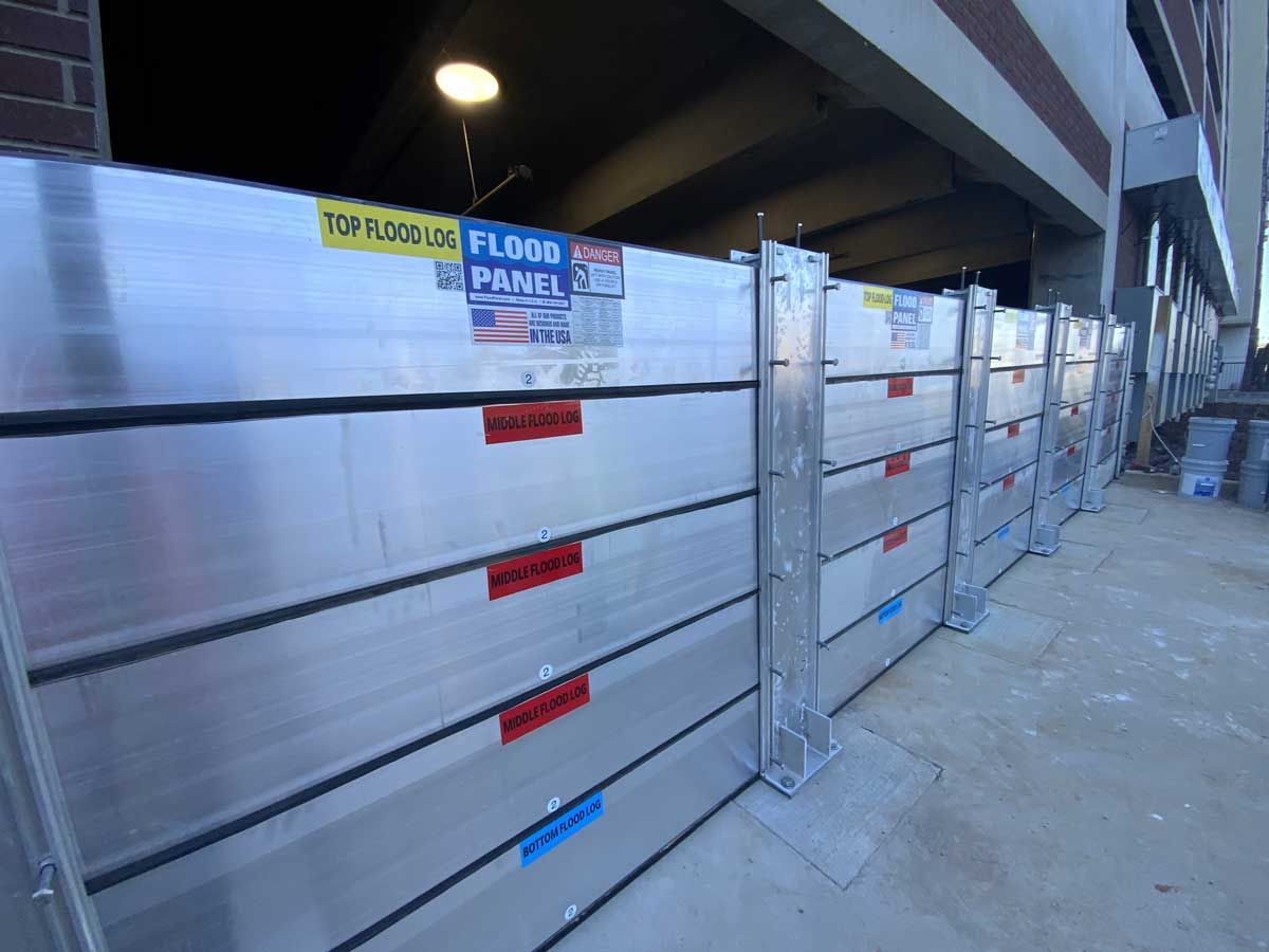 A row of aluminum flood panels are sitting in front of a building.