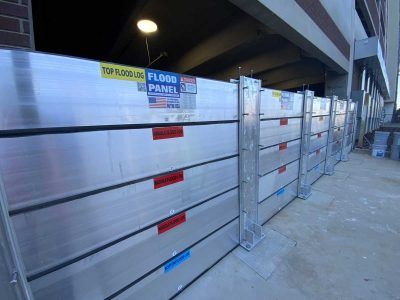 A row of aluminum flood panels are lined up in front of a building.