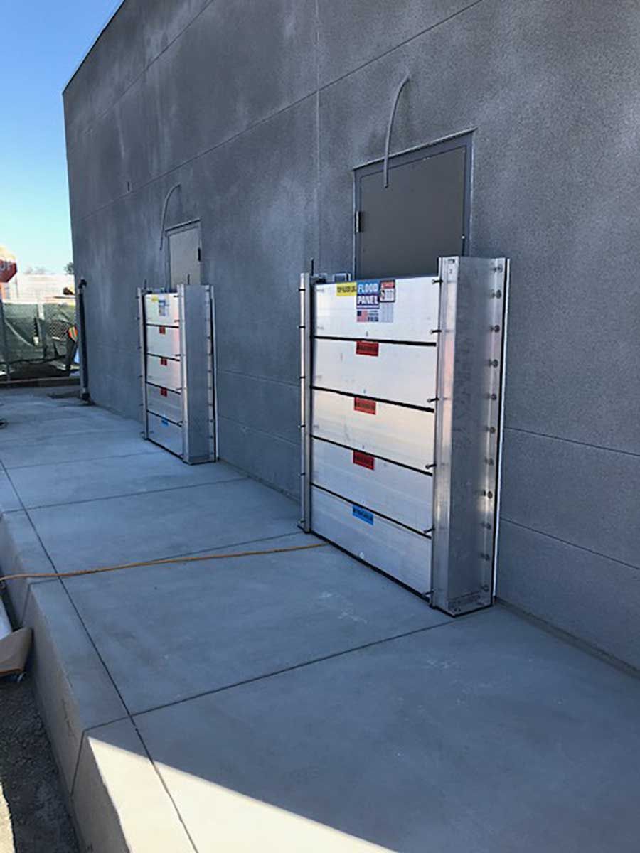 A row of flood barriers are sitting on the sidewalk in front of a building.